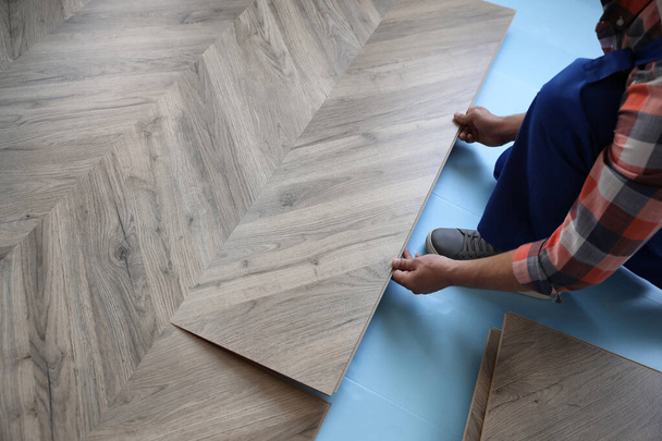 Worker installing laminated wooden floor indoors, closeup - Фото, зображення