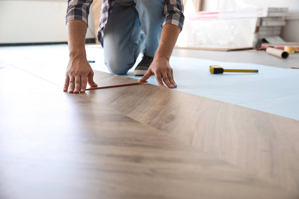 Worker installing laminated wooden floor indoors, closeup - Foto, Imagen