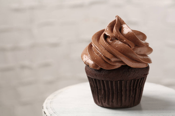 Delicious chocolate cupcake with cream on white table, closeup. Space for text - Foto, Imagem