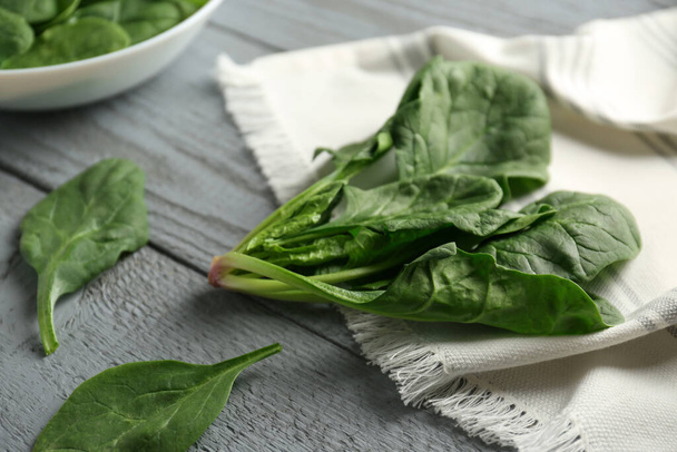 Verse groene gezonde spinazie bladeren op grijze houten tafel, close-up - Foto, afbeelding