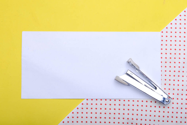Stapler and empty white paper with a colored background. Empty white paper for copy space - Photo, Image