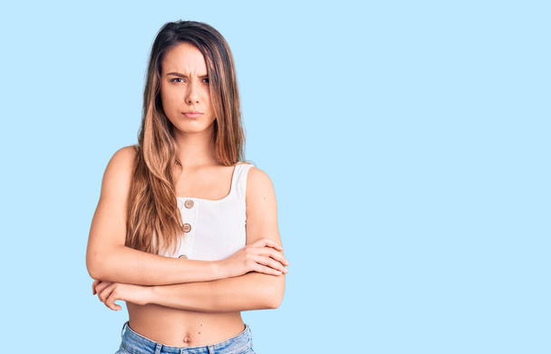 Young beautiful girl wearing casual sleeveless t shirt skeptic and nervous, disapproving expression on face with crossed arms. negative person.  - Photo, Image