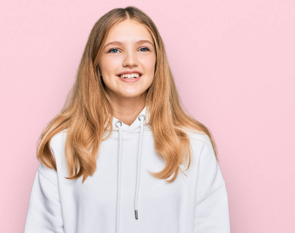 Beautiful young caucasian girl wearing casual sweatshirt looking away to side with smile on face, natural expression. laughing confident.  - Foto, imagen