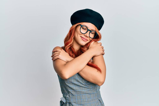 Young redhead woman wearing fashion french look with beret hugging oneself happy and positive, smiling confident. self love and self care  - Photo, Image