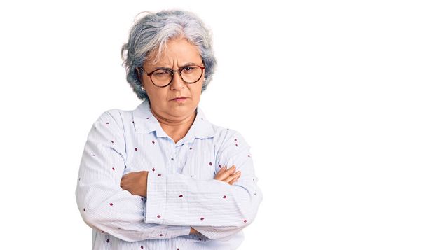 Starsza kobieta z siwymi włosami w luźnych ubraniach biznesowych i okularach sceptyczna i nerwowa, dezaprobata wyraz twarzy z skrzyżowanymi ramionami. osoba negatywna.  - Zdjęcie, obraz