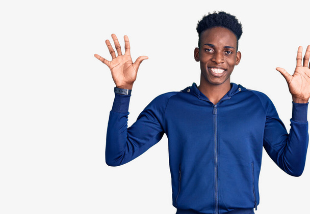 Молодий афроамериканець у спортивній манері показує і вказує вгору з пальцями номер десять, посміхаючись впевнено і щасливо.  - Фото, зображення