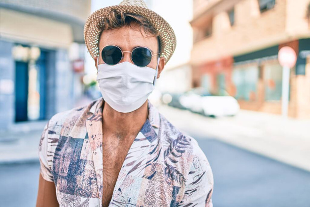 Nuori latino mies lomalla yllään lääketieteellinen naamio kävely kadulla kaupungin - Valokuva, kuva