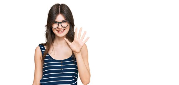 jong mooi blank meisje dragen casual kleding en bril tonen en wijzen met vingers nummer vijf terwijl glimlachen zelfverzekerd en gelukkig.  - Foto, afbeelding