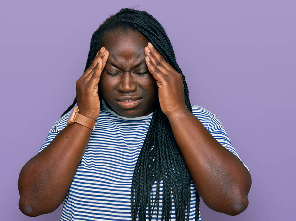 Jonge zwarte vrouw met vlechten in casual kleding met de hand op het hoofd voor pijn in het hoofd omdat stress. lijden aan migraine.  - Foto, afbeelding