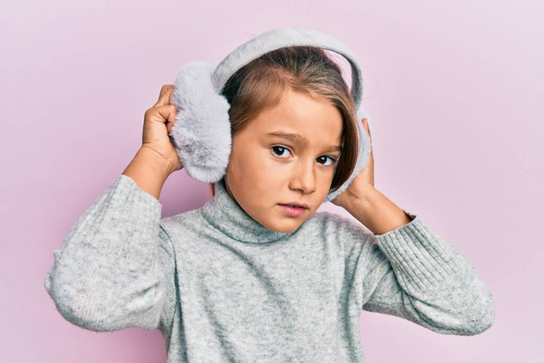 Little beautiful girl wearing fluffy earmuff skeptic and nervous, frowning upset because of problem. negative person.  - Foto, immagini
