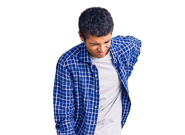 Νεαρός Αφροαμερικάνος που φοράει καθημερινά ρούχα και υποφέρει από οσφυαλγία, αγγίζοντας την πλάτη με το χέρι, μυϊκός πόνος.  - Φωτογραφία, εικόνα