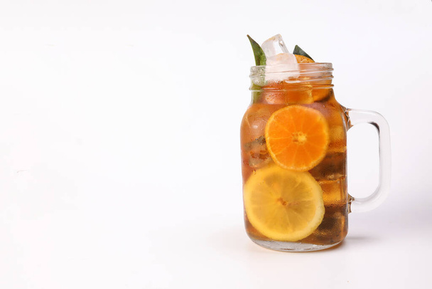 Chá de laranja de limão de gelo líquido com vara de canela de folha verde em caneca de vidro transparente no fundo branco - Foto, Imagem