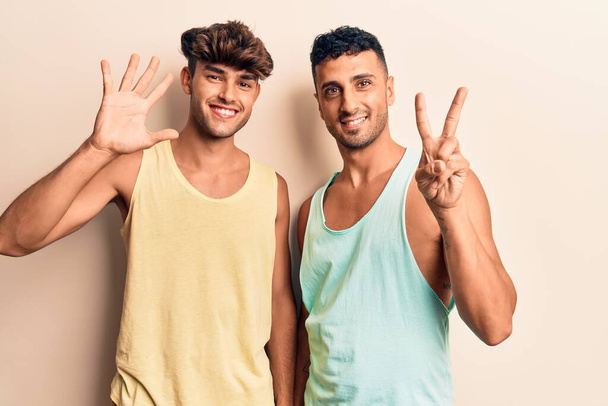 jong gay paar dragen casual kleding tonen en wijzen omhoog met vingers nummer zeven terwijl glimlachen zelfverzekerd en gelukkig.  - Foto, afbeelding
