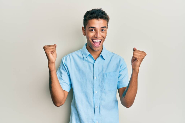 Young handsome african american man wearing casual clothes screaming proud, celebrating victory and success very excited with raised arms  - Photo, Image