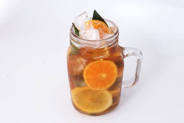 Folyékony jég citrom narancs tea szelet zöld levél fahéj bot átlátszó üveg bögre fehér alapon - Fotó, kép
