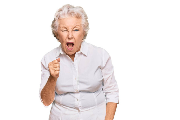 Senior mulher de cabelos grisalhos vestindo roupas casuais com raiva e louco levantando punho frustrado e furioso enquanto gritando com raiva. raiva e conceito agressivo.  - Foto, Imagem