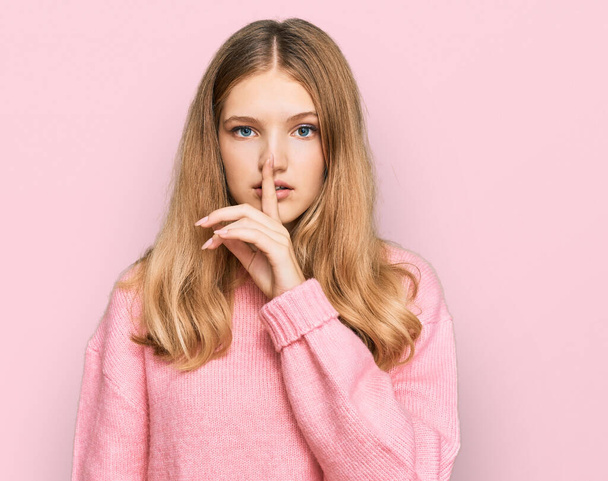 Beautiful young caucasian girl wearing casual winter sweater asking to be quiet with finger on lips. silence and secret concept.  - Foto, immagini