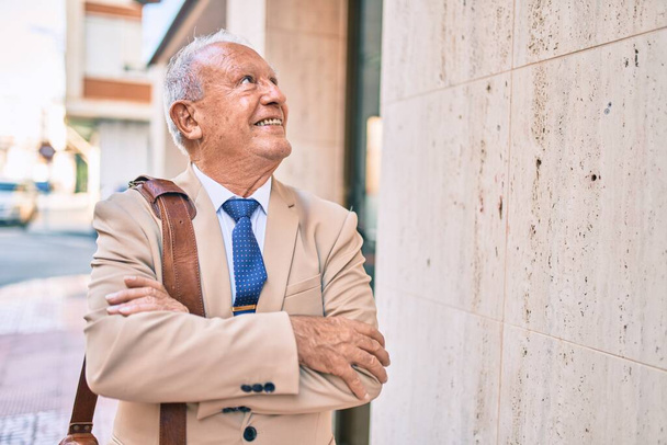 Старший сіроокий бізнесмен усміхнений щасливий стоячи в місті
. - Фото, зображення