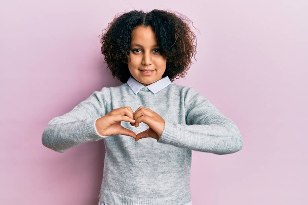 Young little girl with afro hair wearing casual clothes smiling in love doing heart symbol shape with hands. romantic concept.  - Photo, image