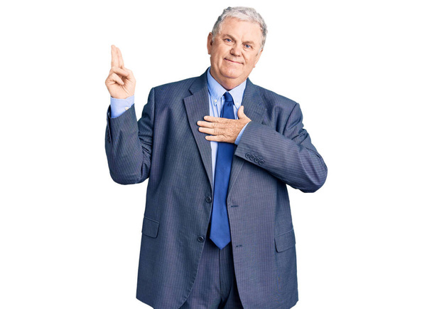 Старший сіро-волохатий чоловік в діловому піджаку посміхається лаятися з рукою на грудях і пальцях вгору, роблячи клятву обіцянки лояльності
  - Фото, зображення
