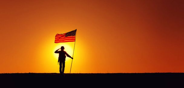 USA Soldaat met vlag salueren op zonsondergang horizon - Foto, afbeelding