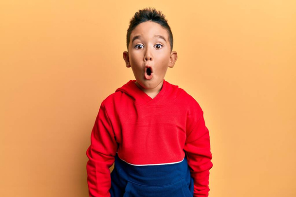 Little boy hispanic kid wearing casual sweatshirt scared and amazed with open mouth for surprise, disbelief face  - Foto, Bild