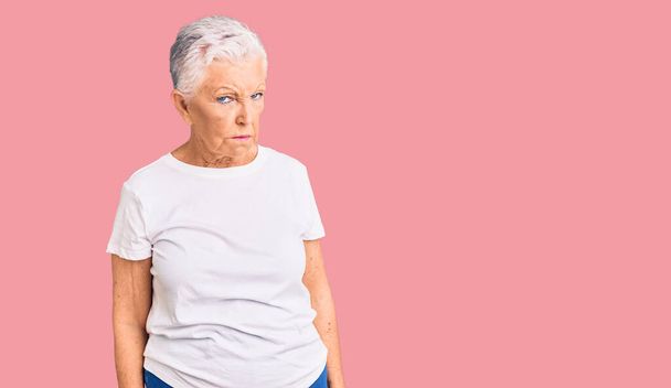 Senior beautiful woman with blue eyes and grey hair wearing casual white tshirt skeptic and nervous, frowning upset because of problem. negative person.  - Photo, Image