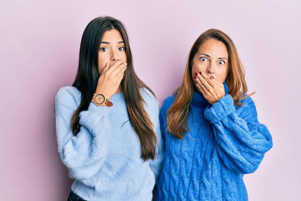 Die hispanische Familie aus Mutter und Tochter, die einen wollenen Winterpullover trug, schockierte, als sie fälschlicherweise den Mund mit den Händen bedeckte. Geheimes Konzept.  - Foto, Bild