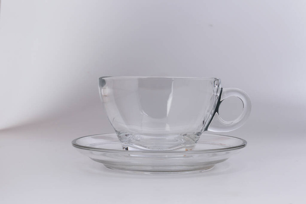 Leeres transparentes Glas durchschauen Kaffeetasse Untertasse auf weißem Hintergrund - Foto, Bild