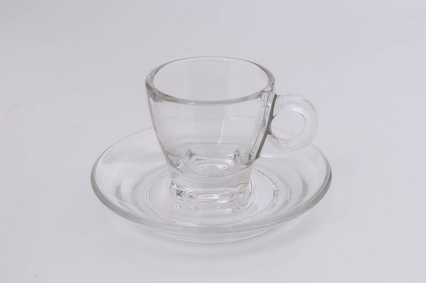 Leeg transparant glas zie door koffiekopje schotel op witte achtergrond - Foto, afbeelding