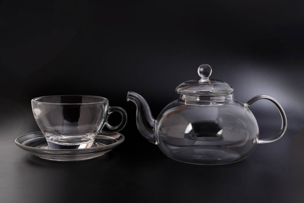 Vidrio transparente vacío ver a través de tetera hervidor de agua taza de té de café platillo conjunto sobre fondo negro - Foto, imagen