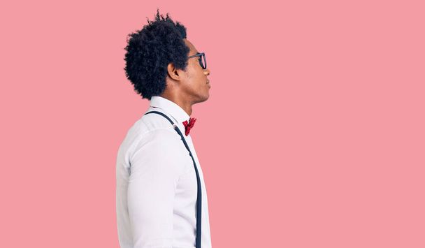 Knappe Afrikaanse Amerikaanse man met afro haar dragen hipster elegante look op zoek naar kant, ontspannen profiel poseren met een natuurlijk gezicht met zelfverzekerde glimlach.  - Foto, afbeelding