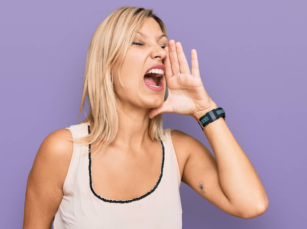 Middelbare leeftijd blanke vrouw draagt casual kleding schreeuwen en schreeuwen luid naar zij met de hand op de mond. communicatieconcept.  - Foto, afbeelding