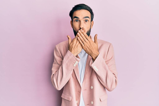 Young hispanic man wearing business jacket shocked covering mouth with hands for mistake. secret concept.  - Photo, Image