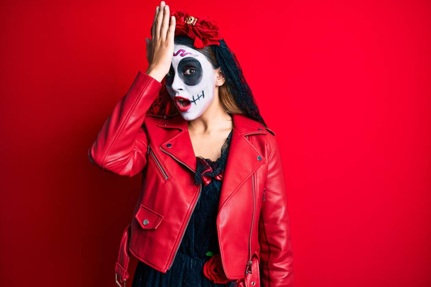 Woman wearing day of the dead costume over red surprised with hand on head for mistake, remember error. forgot, bad memory concept.  - Foto, imagen