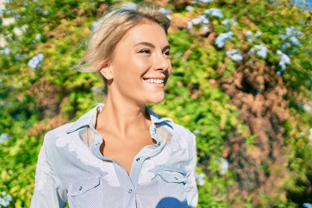 Mladá blondýnka žena usměvavá šťastný chůze v parku. - Fotografie, Obrázek