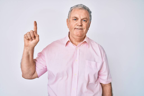 Старший седовласый мужчина в обычной одежде, улыбающийся с идеей или вопросом, показывая пальцем вверх со счастливым лицом, номер один  - Фото, изображение