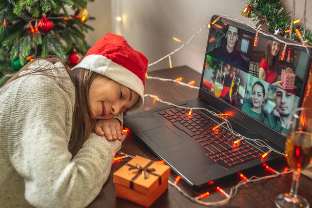 Nuori nainen nukahti tietokoneen näytön eteen kommunikoidessaan ystävien ja sukulaisten kanssa videolinkin kautta. Konsepti kauko joulun ja uudenvuoden osapuolille - Valokuva, kuva
