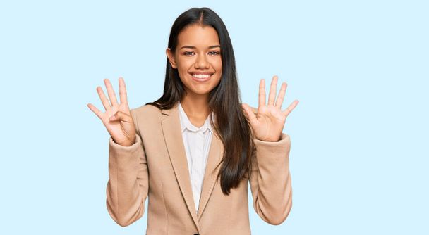 Красива іспаномовна жінка в діловому піджаку показує і вказує пальцями номер дев'ять, посміхаючись впевнено і щасливо
.  - Фото, зображення