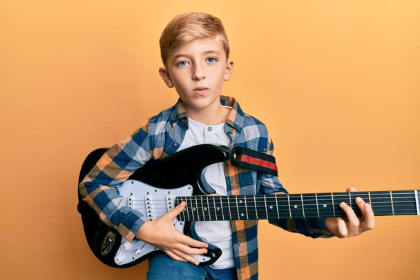 Little caucasian boy kid playing electric guitar looking at the camera blowing a kiss being lovely and sexy. love expression.  - Фото, изображение