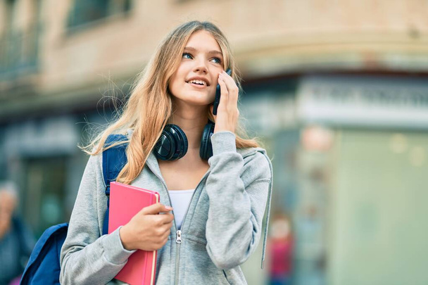 Красивая кавказская студентка-подросток улыбается счастливо разговаривая по смартфону в городе. - Фото, изображение