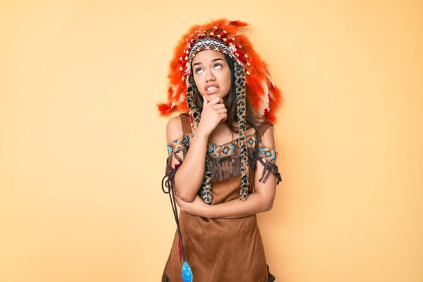 Young beautiful latin girl wearing indian costume thinking worried about a question, concerned and nervous with hand on chin  - Foto, Bild