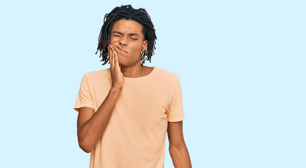 Junge afrikanisch-amerikanische Mann in lässiger Kleidung berühren Mund mit der Hand mit schmerzhaftem Gesichtsausdruck wegen Zahnschmerzen oder Zahnerkrankungen an den Zähnen. Zahnarzt  - Foto, Bild