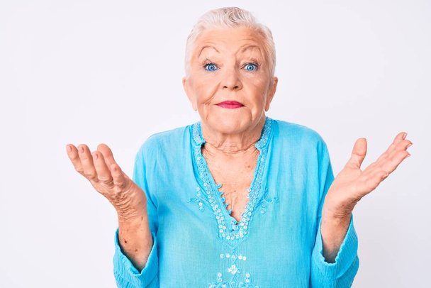 Senior krásná žena s modrýma očima a šedé vlasy na sobě letní oblečení bezradný a zmatený s otevřenou náručí, nemám ponětí a pochybné tvář.  - Fotografie, Obrázek