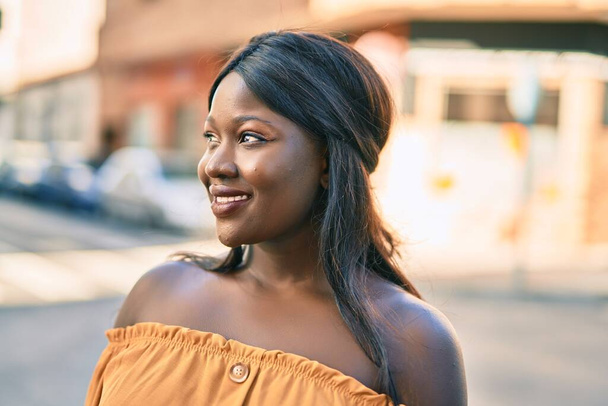 若いアフリカ系アメリカ人の女性が幸せそうに街に立っている. - 写真・画像