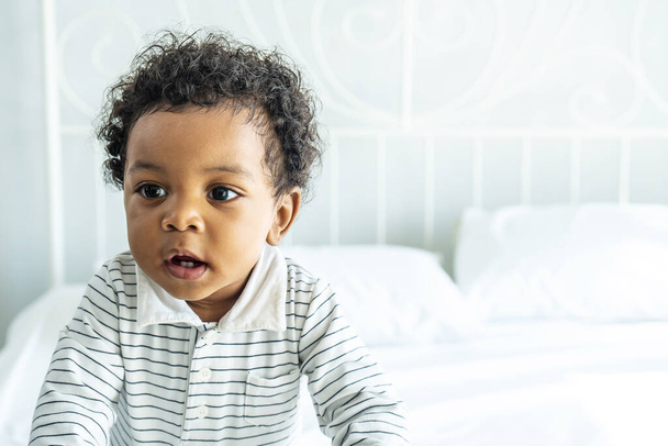 Yatağın üzerinde pofuduk saçlı sevimli Afrikalı bebek, tatlı çocuk. - Fotoğraf, Görsel