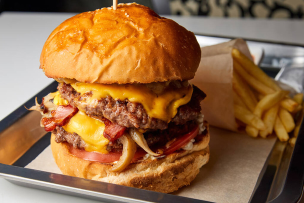Burger marhahússal, sajttal és sült krumplival. Közelkép, szelektív fókusz - Fotó, kép
