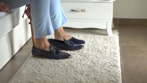 A man in a suit sits on a bed and shoes - Video