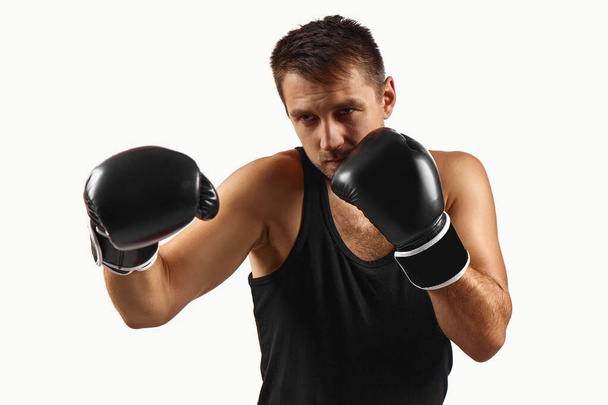 sporty man in black boxing gloves punching - Foto, afbeelding