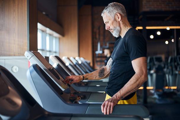 Sportsman pressing the start button on the cardio machine - Valokuva, kuva